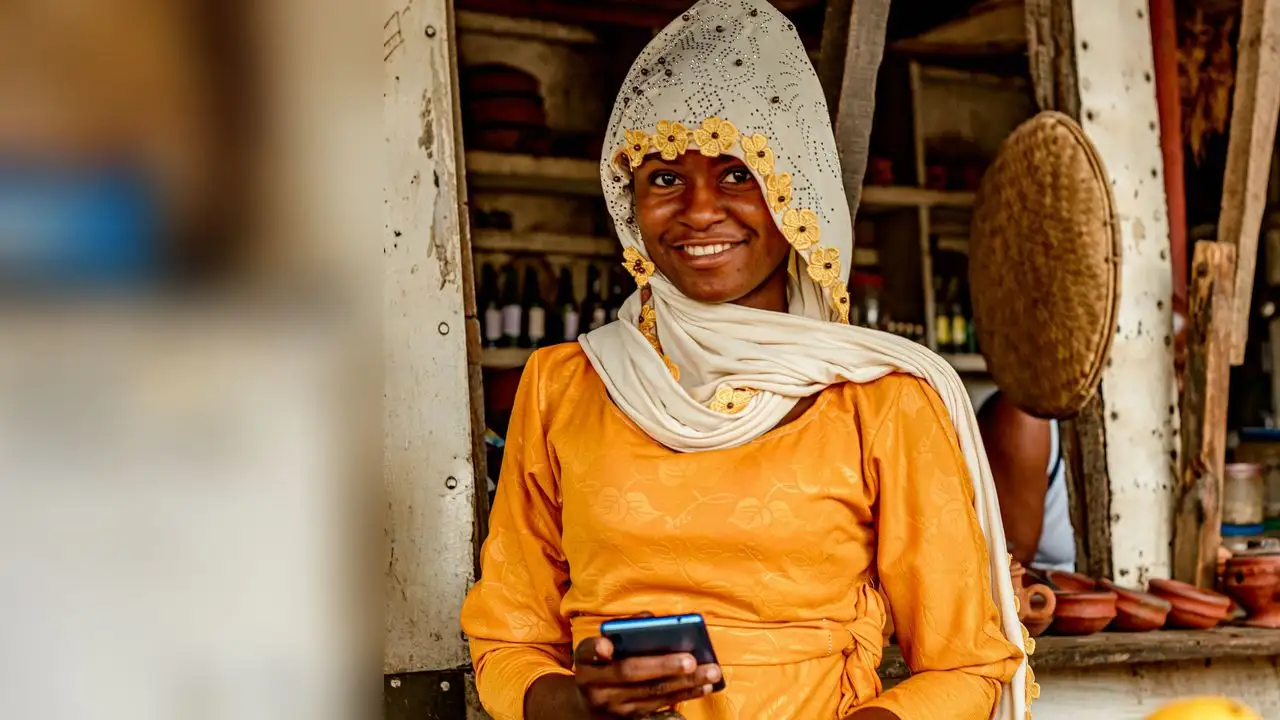Une commerçante sur un marché, téléphone en main